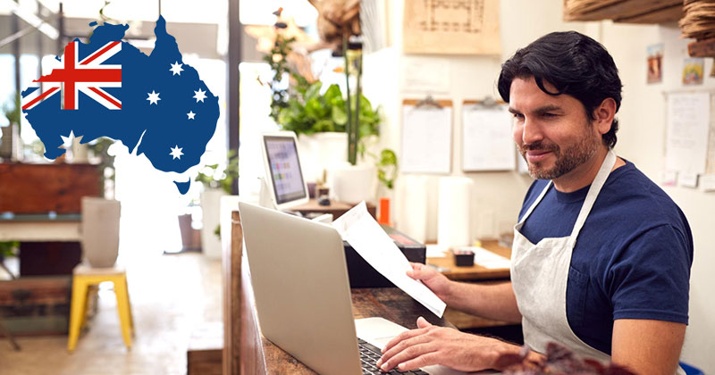 dropshipping suppliers australia - Man looking at laptop screen wearing an apron in a store